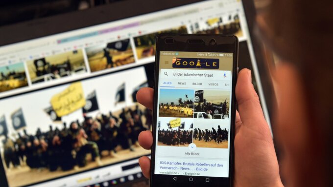 Eine Person betrachtet auf Smartphone und Laptop Bilder, die Aktivitäten des sogenannten Islamischen Staates darstellen.
